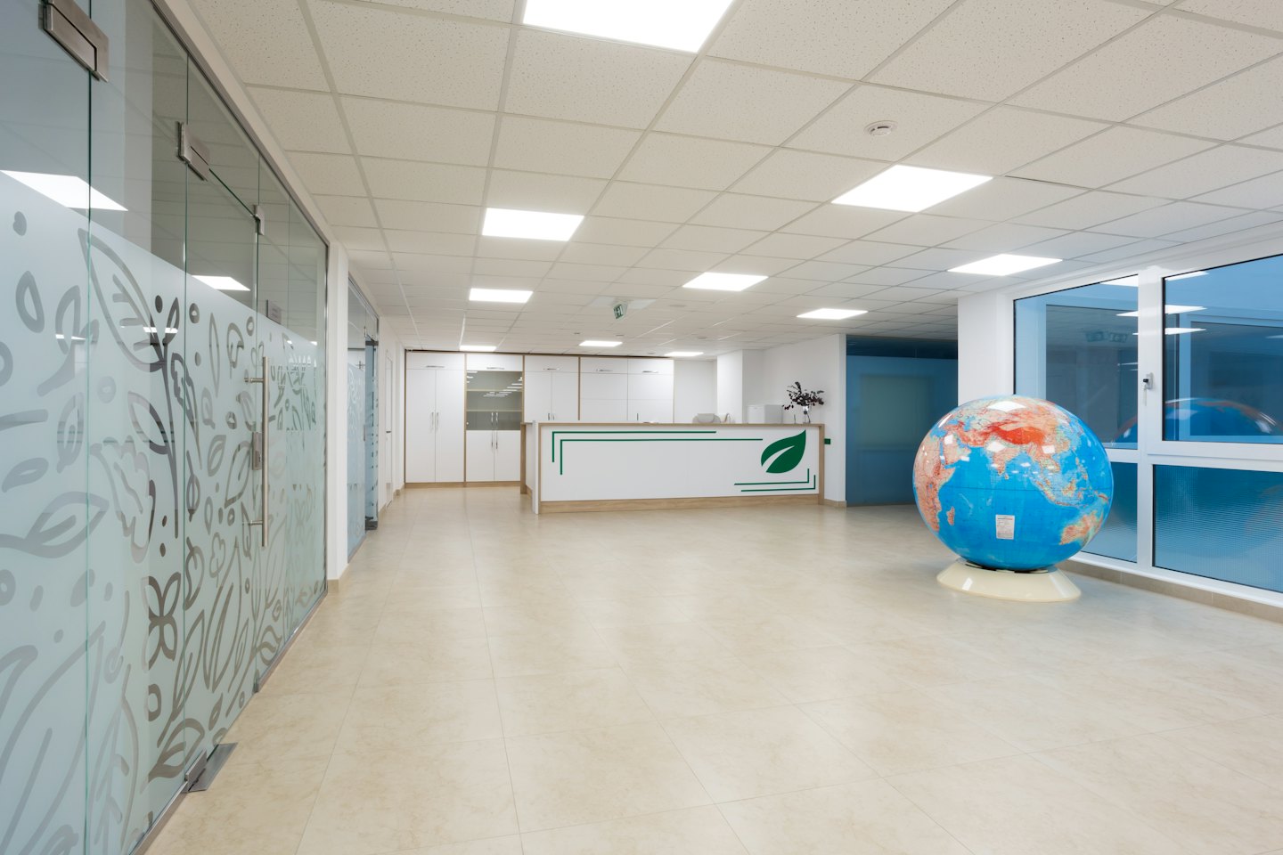 Modern office reception desk with globe and frosted glass partitions.