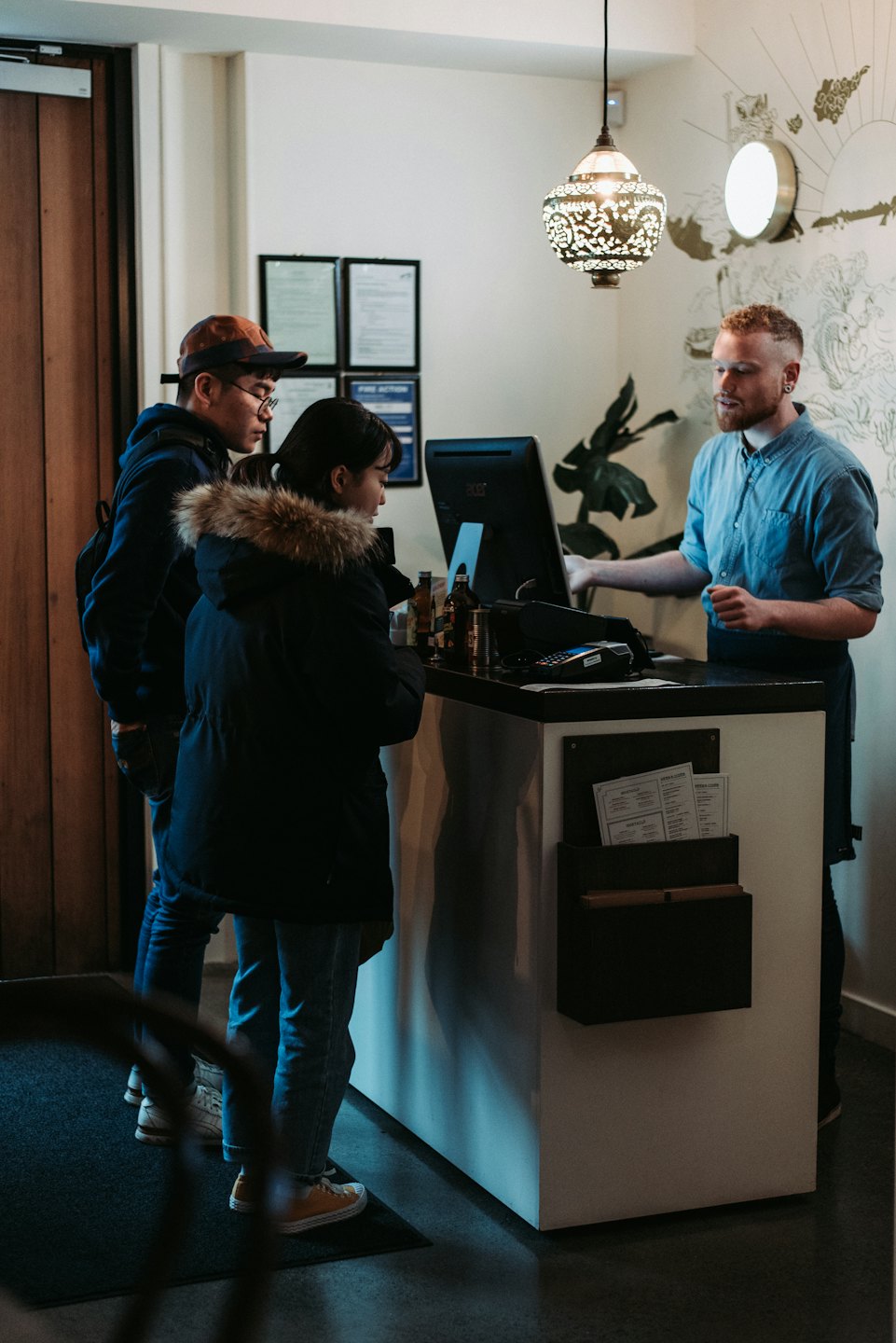Staff member helps customers at a reception desk.